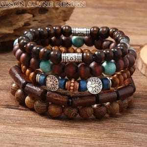 May include: A stack of wooden bead bracelets in brown, turquoise, and silver tones. The bracelets feature a mix of bead sizes and shapes, including cylindrical and round beads. Some have silver accents and tree of life charms.