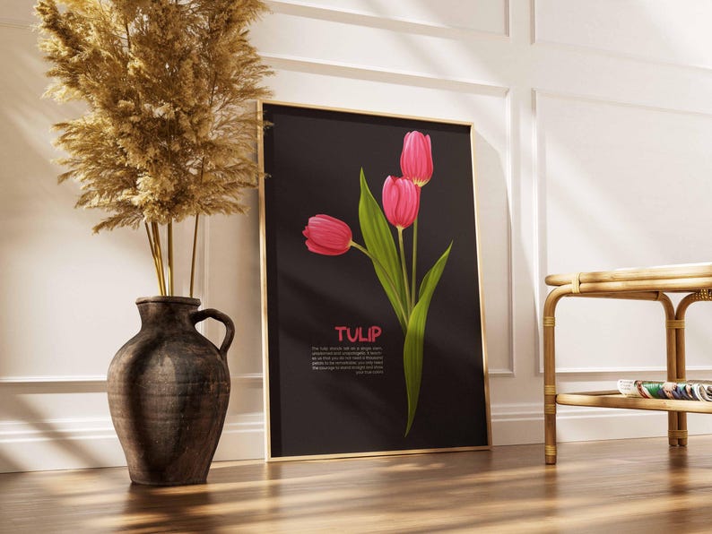 May include: A framed art print featuring three pink tulips with green leaves against a black background. The word "TULIP" is displayed in pink text. The print is leaning against a white wall next to a decorative vase.