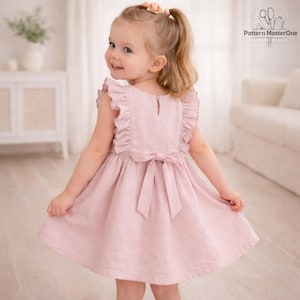 May include: A light pink dress with ruffled sleeves and a bow in the back. The dress is made of a soft fabric and has a simple, elegant design. The dress is suitable for a young child.