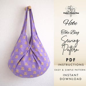 May include: A lavender tote bag with a repeating pattern of tan teddy bears hangs from a wooden peg. The bag has long straps and a rounded bottom. Text on the right side reads "Hobe Tote Bag Sewing Pattern PDF Instructions".