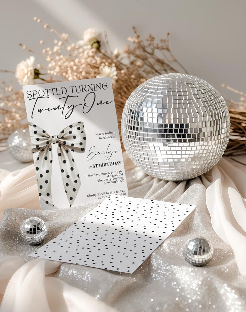 May include: A white rectangular birthday invitation card featuring a large black polka dot bow graphic and the text SPOTTED TURNING Twenty-One, Emily's 21ST BIRTHDAY, and event details. A matching polka dot card and a large silver disco ball are present.