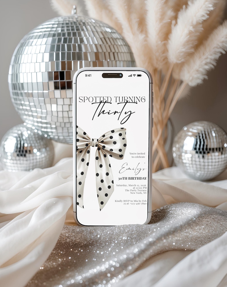 May include: A smartphone displaying a digital invitation for a 30th birthday party. The screen features the text Spotted Turning Thirty, a graphic of a cream-colored bow with black polka dots, and event details including date, time, and location.