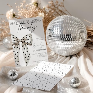 May include: A white birthday invitation card featuring the text Spotted Turning Thirty, a large black and white polka dot bow graphic, and event details for Emily's 30th birthday. A matching polka dot card and a silver mirrored disco ball are present.