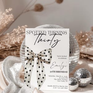Op de afbeelding: Een verjaardagsuitnodiging met de tekst "Spotted Turning Thirty" en een strik met zwarte stippen. De uitnodiging bevat details voor een 30e verjaardagsviering, met een discobal op de achtergrond.