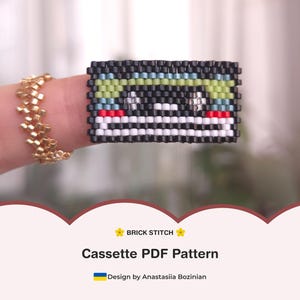 Puede incluir: Un diseño de cinta de cassette con cuentas en negro, verde, blanco, rojo y azul. El diseño está hecho con la técnica de puntada de ladrillo. La imagen también muestra un anillo de cuentas de oro. El texto de la imagen dice "Cassette PDF Pattern".