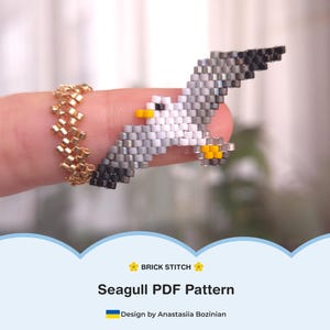 May include: A detailed beaded seagull in flight, made with white, grey, black, and yellow beads. The seagull is held by a finger wearing a gold beaded ring. The image includes the text "Seagull PDF Pattern" and "Brick Stitch".