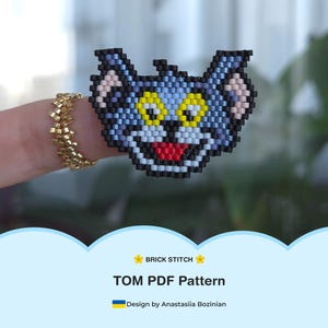 Puede incluir: Una taza de cerámica blanca con un asa negra y el texto "But First, Coffee" en negrita negra. La taza se encuentra sobre un fondo borroso, sugiriendo un ambiente acogedor.