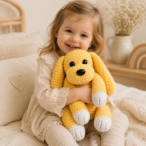 May include: A handmade crochet stuffed dog toy featuring bright yellow yarn, long floppy ears, and white yarn accents on the paws. The plush animal has two round black plastic eyes and a black plastic nose, creating a soft and textured appearance.