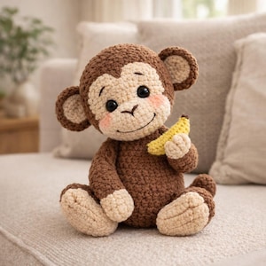 May include: A handmade crochet monkey doll in shades of brown and beige, holding a yellow banana. The monkey has a smiling face with rosy cheeks and large black eyes. The plush toy is sitting on a light-colored surface.