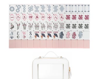 Puede incluir: Un juego de fichas de mahjong rectangulares con reverso rosa y frente blanco con varios diseños impresos que incluyen números, caracteres chinos, dragones, flores, abanicos y la palabra JOKER, junto con un estuche blanco con una ventana transparente.