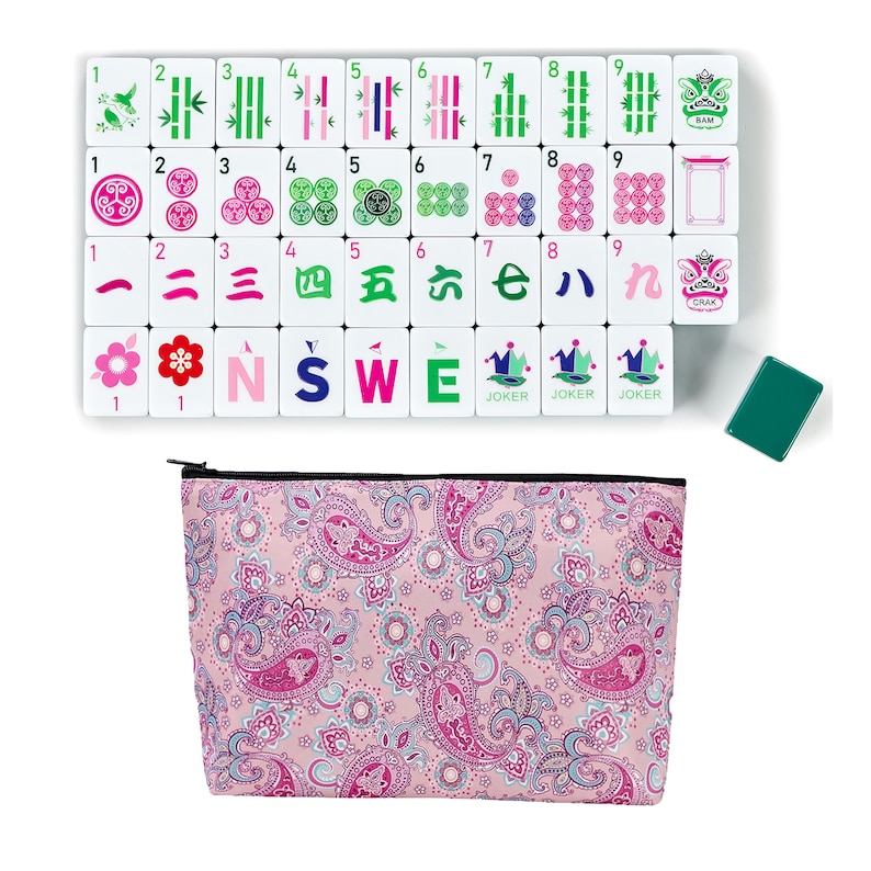 Puede incluir: Un juego de Mahjong completo con fichas blancas que presentan varios s&iacute;mbolos y n&uacute;meros, incluyendo bamb&uacute;, c&iacute;rculos y caracteres. El juego incluye una bolsa con cremallera con estampado de cachemira rosa y una ficha verde. Las fichas est&aacute;n dispuestas sobre una superficie blanca.