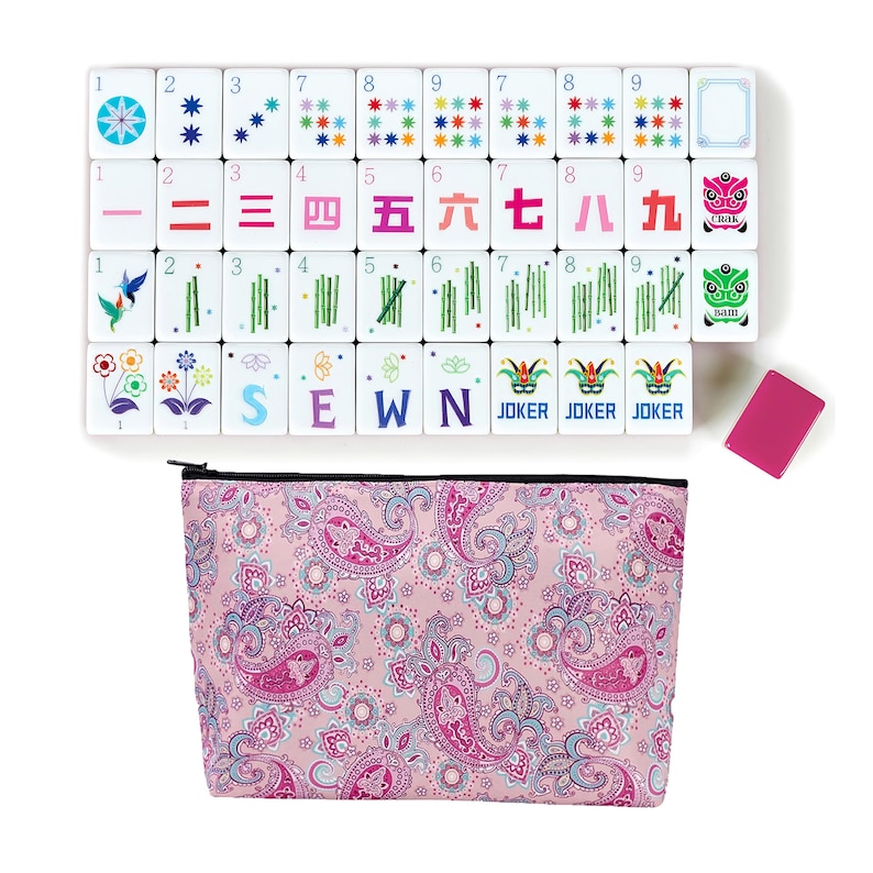 May include: A Mahjong set with white tiles displaying symbols and numbers. The set includes a pink paisley-patterned zippered pouch, a pink tile, and tiles with the word "SEWN".