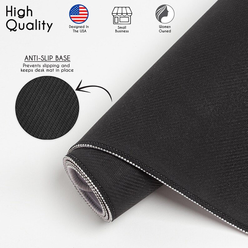 May include: A black desk mat with a textured surface and stitched edges. The image includes text stating High Quality, Designed In The USA, Small Business, Women Owned, and ANTI-SLIP BASE Prevents slipping and keeps desk mat in place.