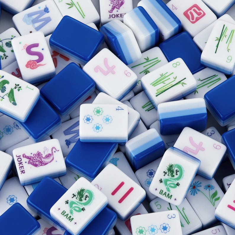 May include: A collection of white and blue Mahjong tiles. The tiles feature various symbols, numbers, and characters in green, pink, and blue. Some tiles have the word "Joker" and "+ BAM +" printed on them.