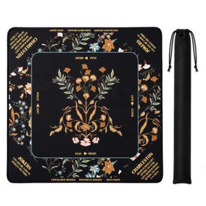 May include: A square black Mahjong mat featuring a central floral pattern in orange, pink, and green, with gold text detailing game rules like Charleston and Jokers. The mat includes directional markers for play and walls, accompanied by a black drawstring bag.