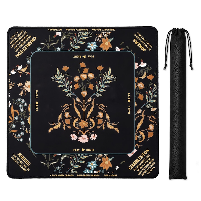 May include: A square black Mahjong mat featuring a central floral pattern in orange, pink, and green, with gold text detailing game rules like Charleston and Jokers. The mat includes directional markers for play and walls, accompanied by a black drawstring bag.
