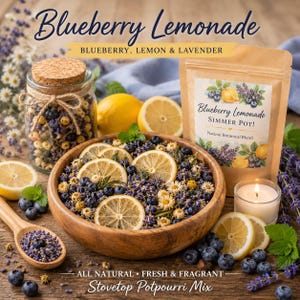 May include: A wooden bowl filled with a stovetop potpourri mix, featuring dried lemon slices, blueberries, and lavender. A jar with a cork lid and a bag of the same mix are also present. The text reads "Blueberry Lemonade".