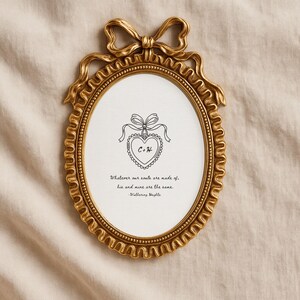 Vintage frame lays on muslin cloth to display a Wuthering Heights print with the quote 'Whatever our souls are made of, his and mine are the same." A concept rendering of a locket with "C" and "H" for the main characters is in the middle.