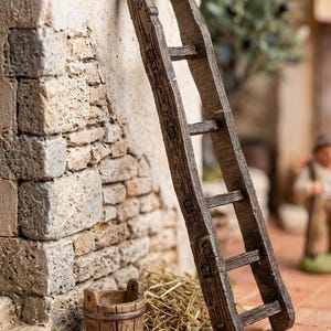 May include: A miniature wooden ladder with a dark brown, weathered texture and five rungs, leaning against a stone wall next to a small, round wooden bucket and a pile of dry straw on a terracotta-colored tiled floor surface.