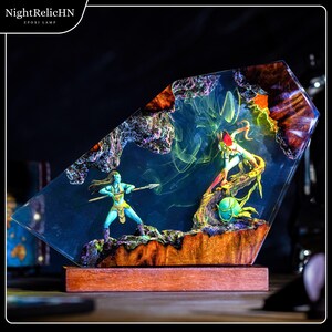 May include: A decorative epoxy lamp featuring a scene with two figures, one holding a spear. The figures are set against a blue background with colorful accents. The lamp sits on a wooden base and has the text "NightRelicHN" and "EPOXI LAMP".