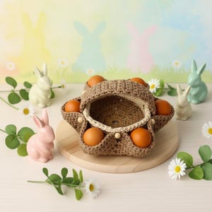 Peut inclure: Un panier à œufs en crochet marron en forme d'étoile, contenant plusieurs œufs bruns. Le panier est posé sur une planche ronde en bois, entouré de lapins en céramique et de marguerites. Le fond présente des silhouettes de lapins pastel.