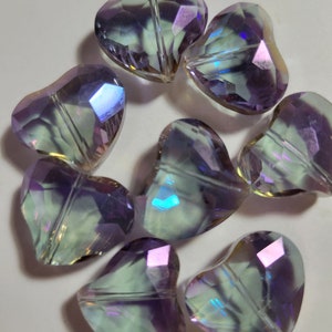 May include: A cluster of iridescent heart-shaped beads. The beads are faceted, reflecting a range of colours including purple, green, and blue. These decorative beads are suitable for jewellery making and craft projects.