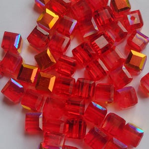 May include: A pile of red square glass beads with iridescent rainbow facets.