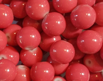 May include: A close-up of a pile of bright red round beads. The beads are smooth and shiny, and they have a slight white center.