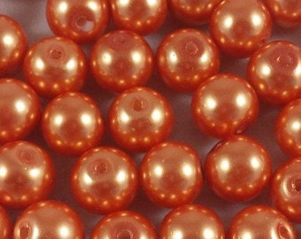 May include: A large group of round, orange pearl beads. The beads have a smooth, shiny finish.