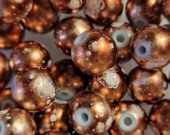 May include: A collection of round, copper-colored beads with white speckles. The beads have a glossy finish and a hole in the center.