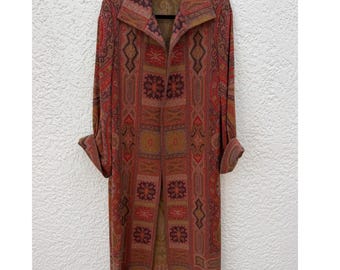 May include: A long-sleeved, open-front duster coat featuring a rich tapestry-style pattern in shades of rust, deep red, gold, and dark brown. The garment has a wide collar, cuffed sleeves, and a structured, straight-cut silhouette with a textured finish.