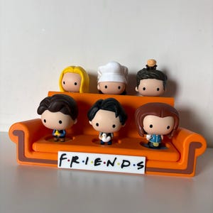 Può includere: Una tazza di ceramica bianca con manico nero e la scritta "But First, Coffee" in nero, con un carattere a mano. La tazza è su una superficie bianca.