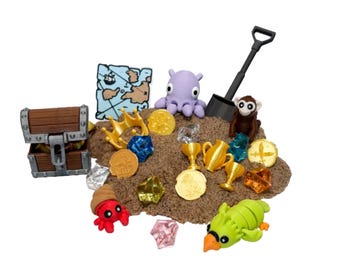 May include: A treasure chest, map, and various toy treasures are arranged on a pile of sand. The scene includes a crown, coins, gems, trophies, and toy creatures like an octopus, monkey, crab, and parrot. A black shovel is also present.