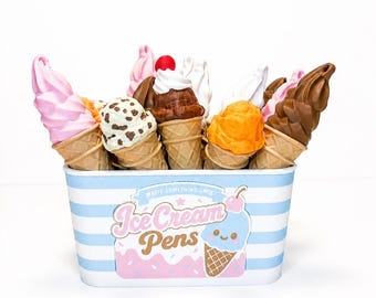 May include: A collection of ice cream cone-shaped pens stored in a light blue and white striped container. The container features the text "Write Something Sweet" and "Ice Cream Pens" with a graphic of a smiling blue ice cream cone.
