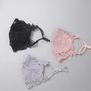 Può includere: Tre mascherine con intricati motivi floreali in pizzo nei colori nero, rosa tenue e grigio chiaro. Ogni mascherina è dotata di elastici regolabili con piccoli cursori in plastica per fissare la vestibilità, mostrando ricami dettagliati e bordi smerlati.