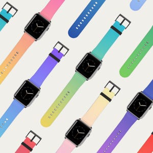 Puede incluir: Una colección de smartwatches con correas de reloj coloridas y degradadas. Las correas transicionan a través de varios tonos, incluyendo rosa, naranja, amarillo, verde y azul. Cada reloj tiene una pantalla negra y una caja plateada, con una hebilla negra.