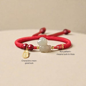 May include: Red braided bracelet with a jade duck charm, gold accents, and a gold charm with Chinese characters. The bracelet also features a koi pattern, symbolizing luck. The characters on the charm mean good luck.