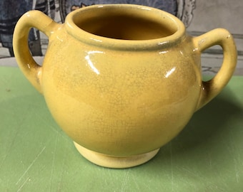 May include: A yellow ceramic creamer with two handles and a crackled glaze.