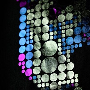 May include: Black fabric with a design of silver, blue, and pink circles arranged in a butterfly shape. The circles vary in size, creating a textured, dimensional effect. The design is set against a dark background.