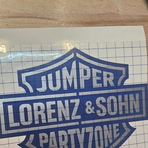 May include: A blue and silver decal featuring the text "JUMPER LORENZ & SOHN PARTYZONE" in a shield design. A brown tool with a curved end is also visible.