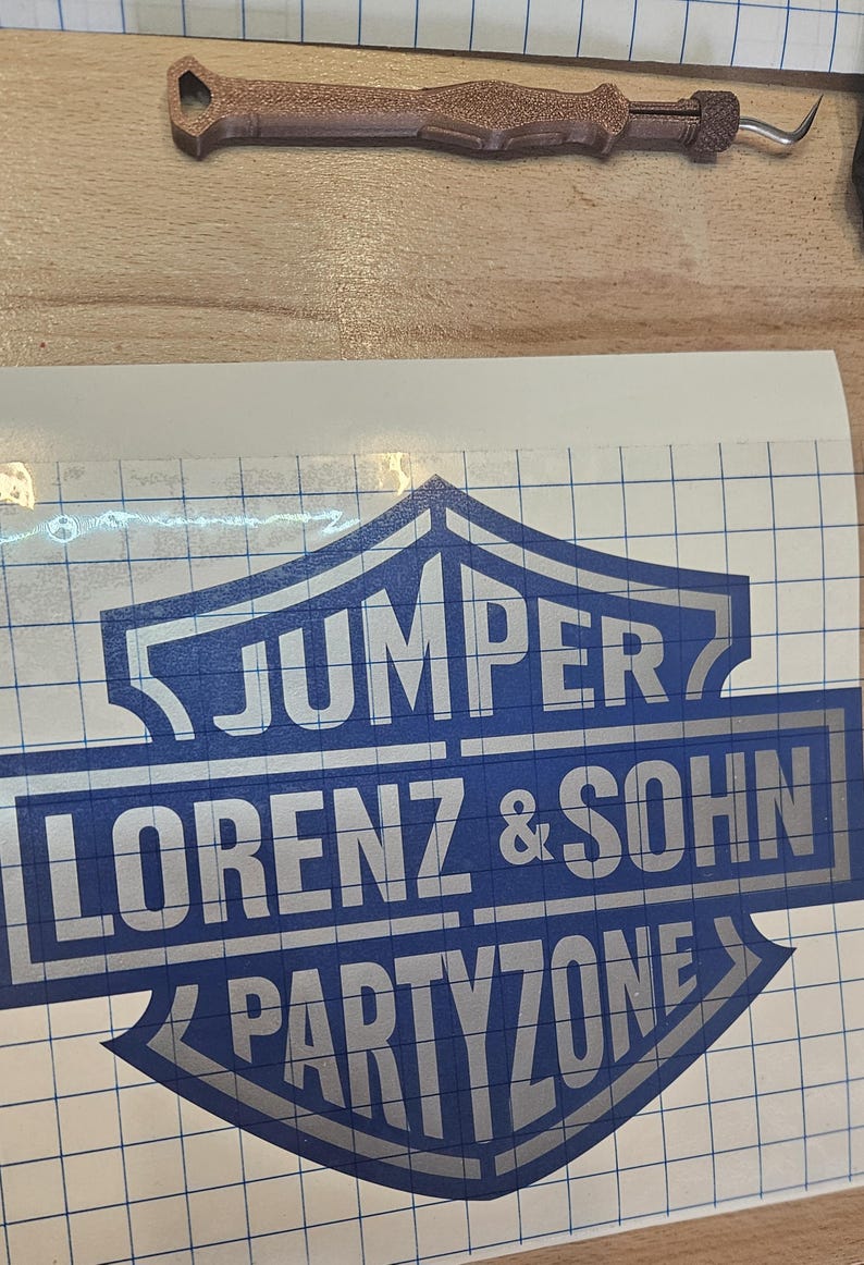 May include: A blue and silver decal featuring the text "JUMPER LORENZ & SOHN PARTYZONE" in a shield design. A brown tool with a curved end is also visible.