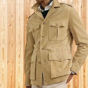 Puede incluir: Chaqueta de ante color beige con múltiples bolsillos delanteros y cierres de botones. La chaqueta tiene cuello y un corte entallado. Las mangas son largas y la chaqueta parece estar hecha de un material suave. La chaqueta es de color neutro.