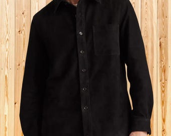 May include: A black button-down shirt with a collared neckline and a single chest pocket. The long-sleeved shirt is made of a soft, suede-like material. The shirt has a classic, casual style.