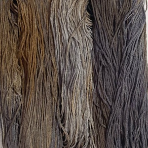 May include: Three skeins of embroidery floss in shades of brown, gray, and purple.