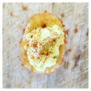 May include: A crispy fried egg cup filled with creamy egg salad and topped with a sprinkle of red pepper flakes.