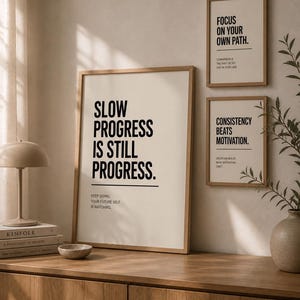 Puede incluir: Tres carteles motivacionales enmarcados con marcos de madera. El cartel más grande dice "SLOW PROGRESS IS STILL PROGRESS". Los otros dos carteles dicen "FOCUS ON YOUR OWN PATH" y "CONSISTENCY BEATS MOTIVATION".
