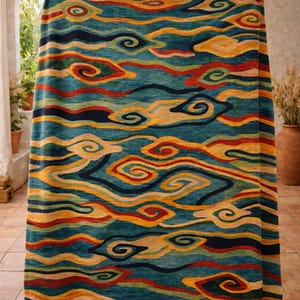Puede incluir: Una manta estampada con un diseño de nubes arremolinadas. La manta presenta un fondo turquesa con acentos amarillos, rojos y azul marino. El diseño recuerda a un cielo estilizado, perfecto para la decoración del hogar.