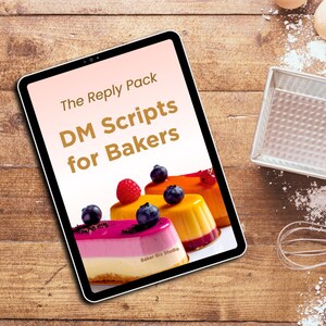 May include: A tablet displays "The Reply Pack DM Scripts for Bakers" with images of colorful desserts. The scene includes baking tools, eggs, and chocolate on a wooden surface, suggesting a baking theme.
