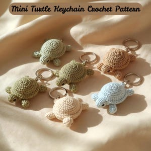 May include: Six crocheted turtle keyrings in shades of green, beige, and blue. Each turtle features a round body, flippers, and a small head, attached to a silver keyring. The text "Mini Turtle Keychain Crochet Pattern" is at the top of the image.