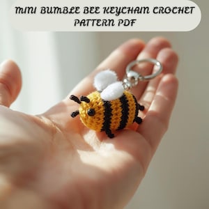 May include: A handmade crochet bumble bee keychain. The bee is yellow with black stripes, white wings, and black legs and antennae. The keychain has a silver-colored ring. Text at the top reads "Mini Bumble Bee Keychain Crochet Pattern PDF."